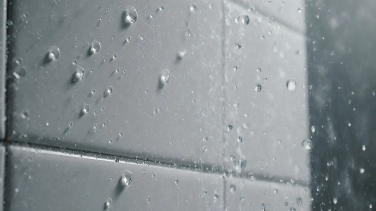 Close-up of water droplets on wet steam room tiles in soft lighting.