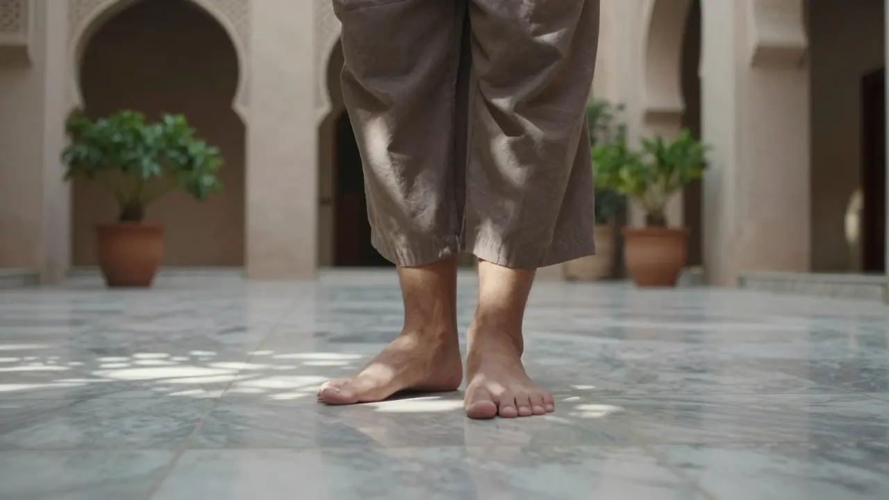 Bare feet walking on cool marble tiles in a shaded Arabic courtyard with soft sunlight.