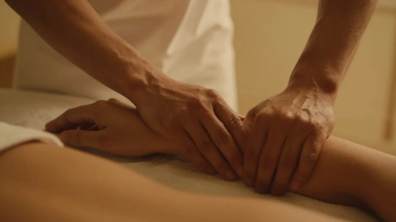 Two hands gently resting on each other's forearms in quiet connection during a massage.